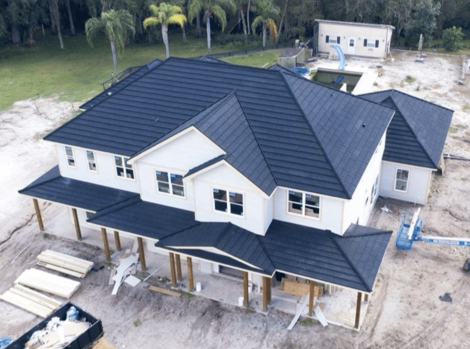 Aerial view of a new two-story home with a dark metal roof during construction