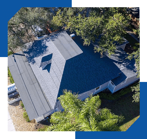 Aerial view of a single-story home with a new gray shingle roof surrounded by trees and palms