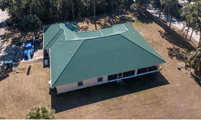 Overhead drone view of a green metal hip roof on a single-story home