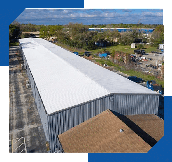 Aerial view of a long commercial metal building with a white roof