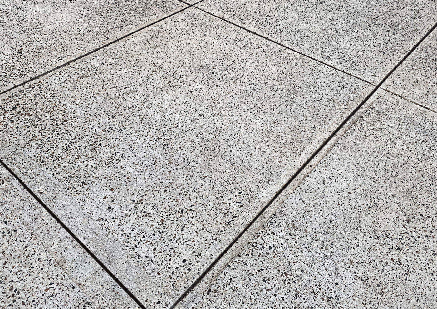 Close-up of a gray speckled concrete surface with joint lines