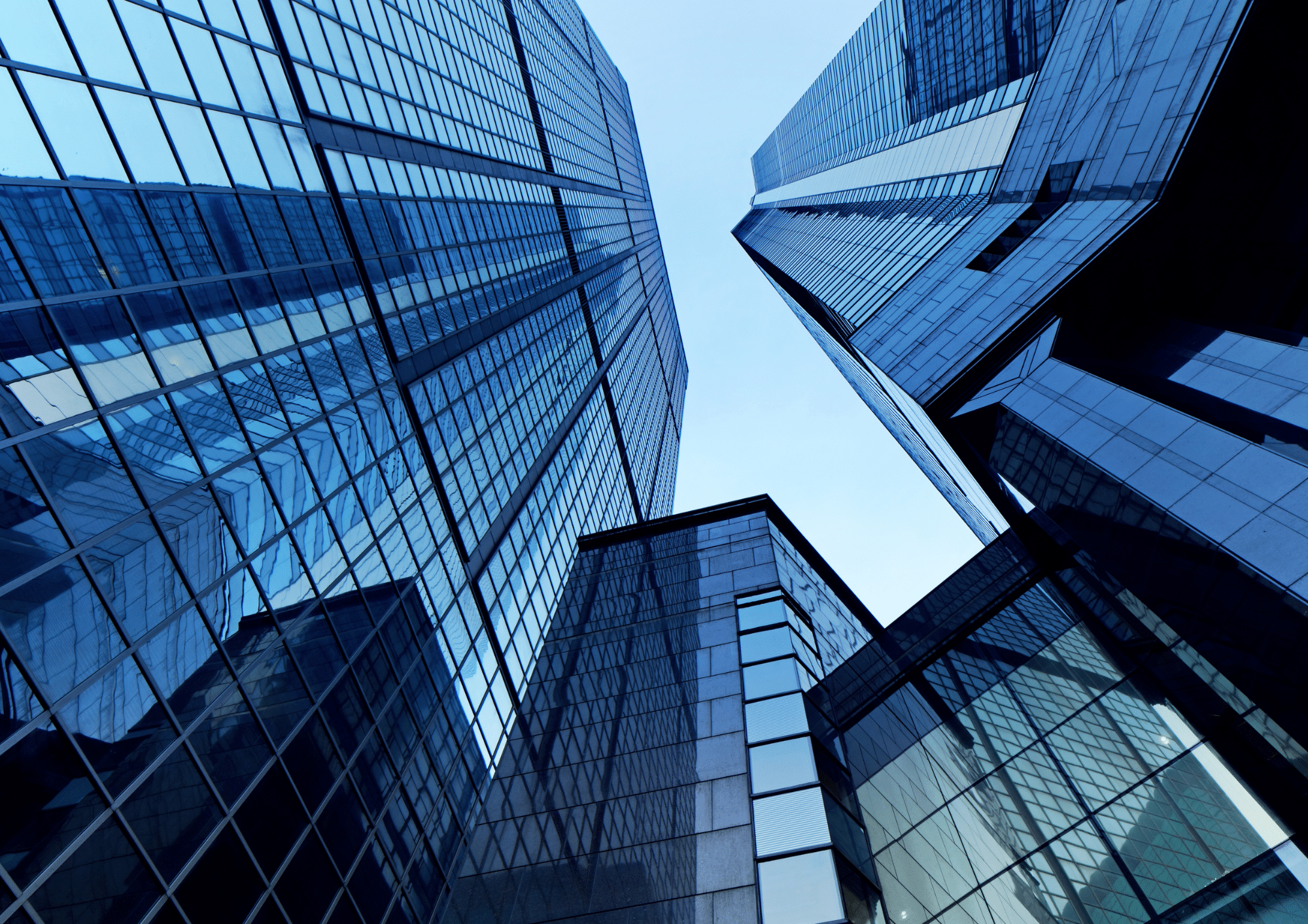 Looking up at glass-walled office towers against a blue sky
