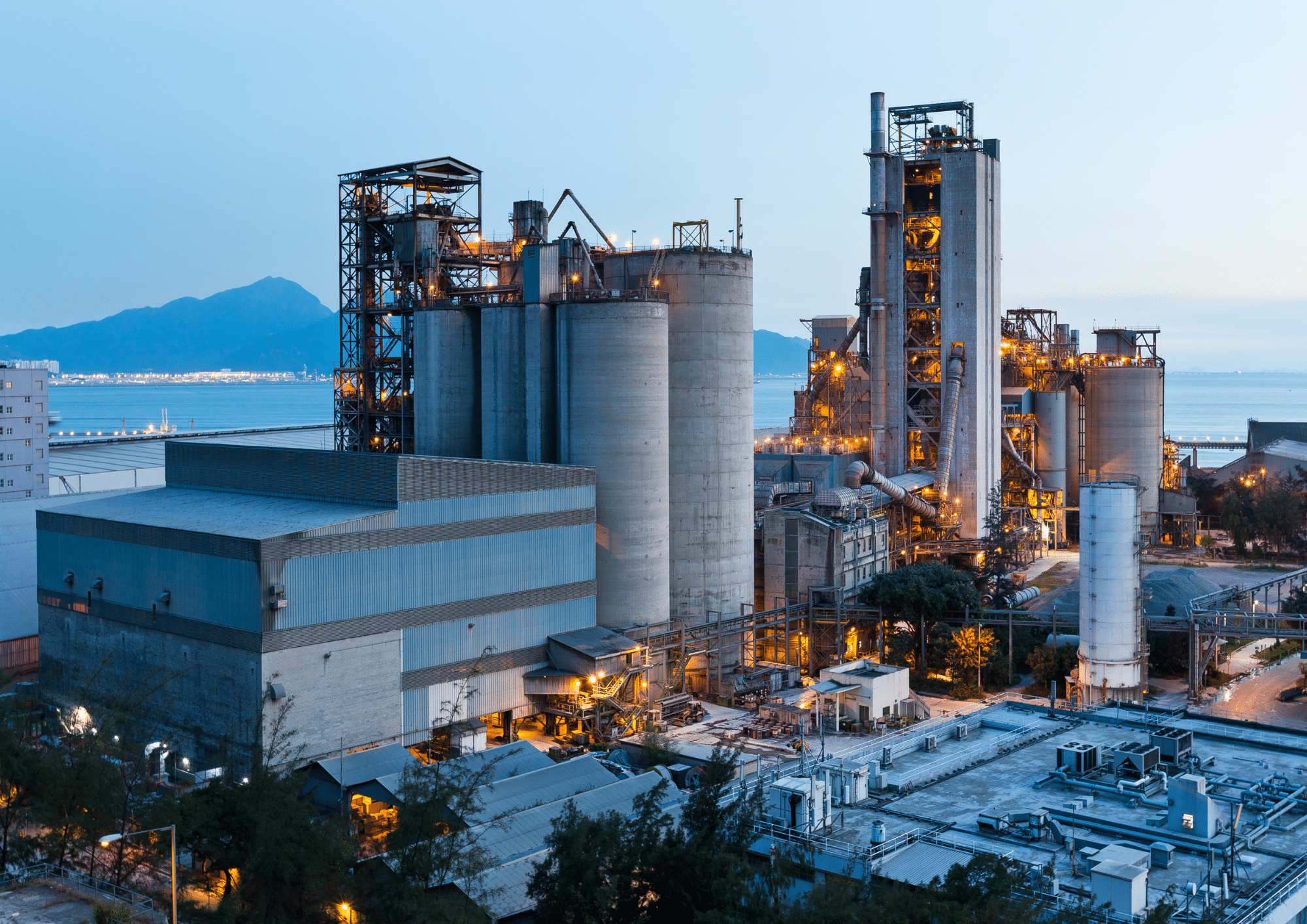 Industrial manufacturing plant with tall silos and metal-roofed buildings at dusk