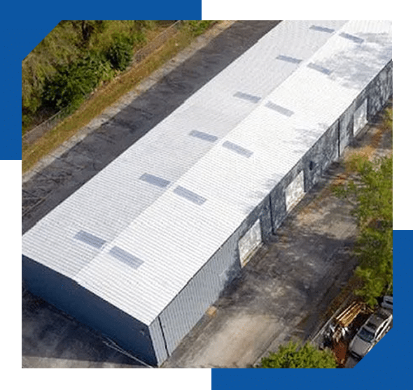 White-coated metal roof with skylight panels on a long warehouse building