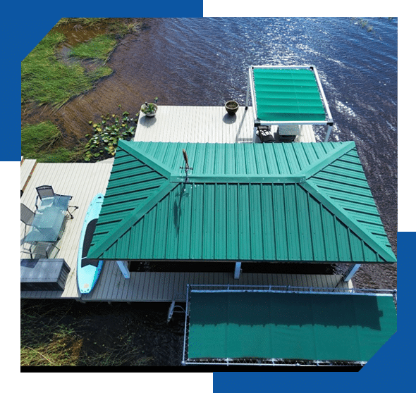 Aerial view of a green standing seam metal roof on a lakeside boathouse and dock