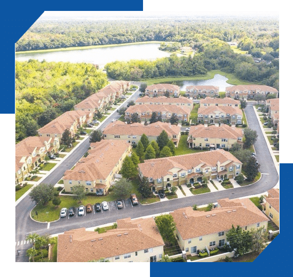 Aerial view of a townhome community with terracotta tile roofs beside a lake